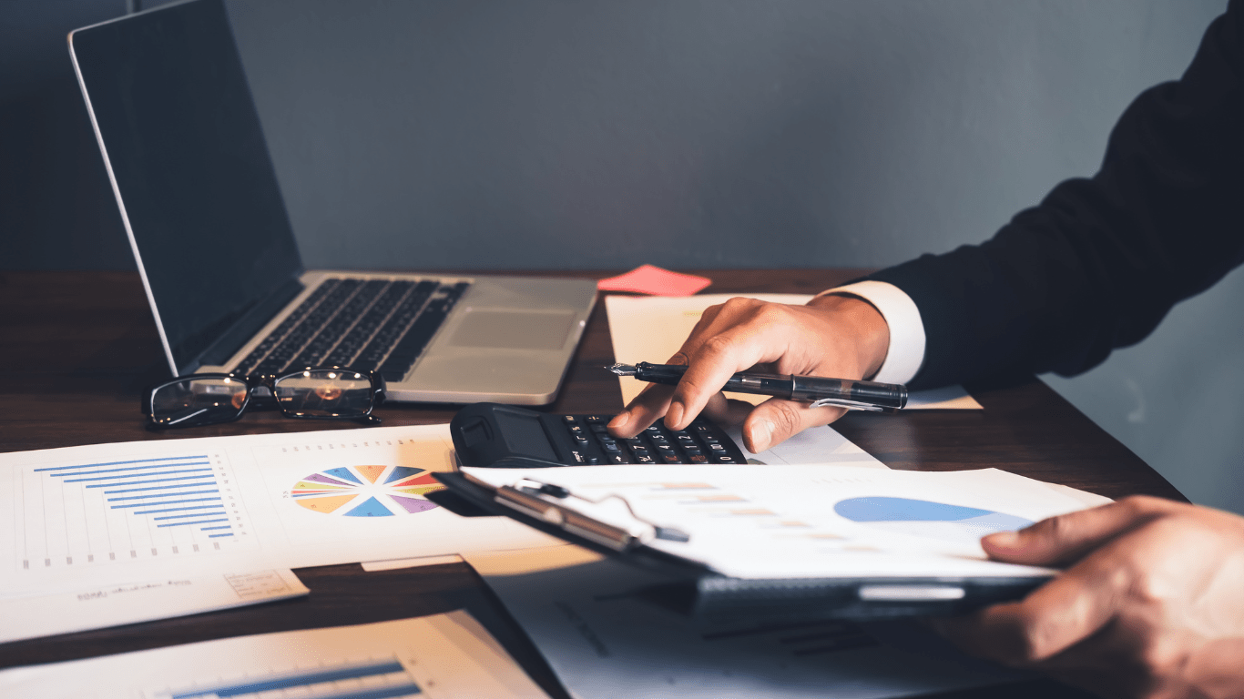 A person's hands on desk with laptop and papers