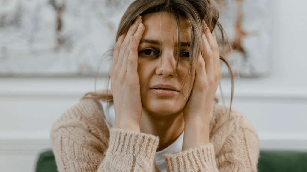 a person sitting with their hands on their face